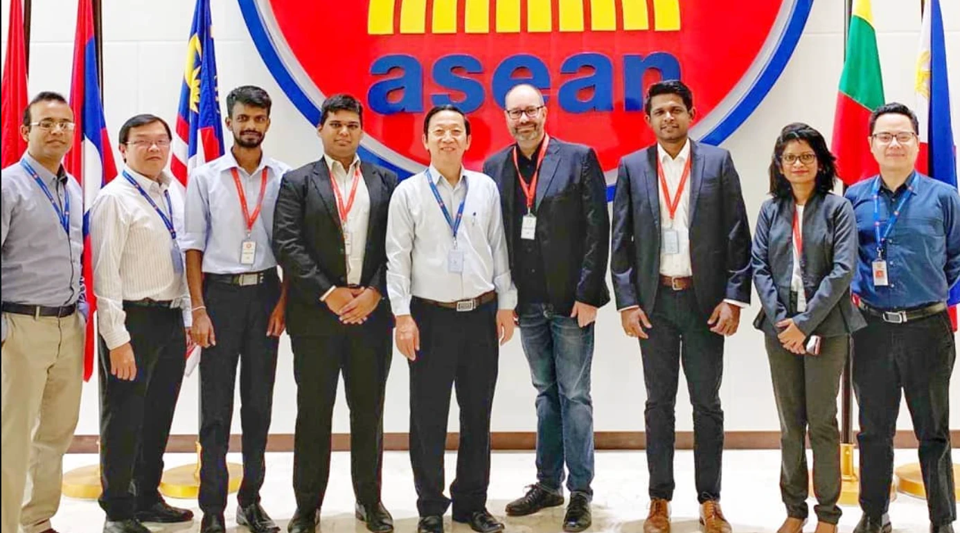 Dulanjaya standing with a group of people in front of a large ASEAN logo and flags